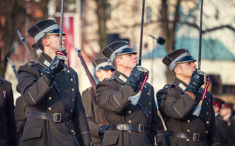 Karavīri ar sarkanbaltsarkanām lentītēm pie apģērba